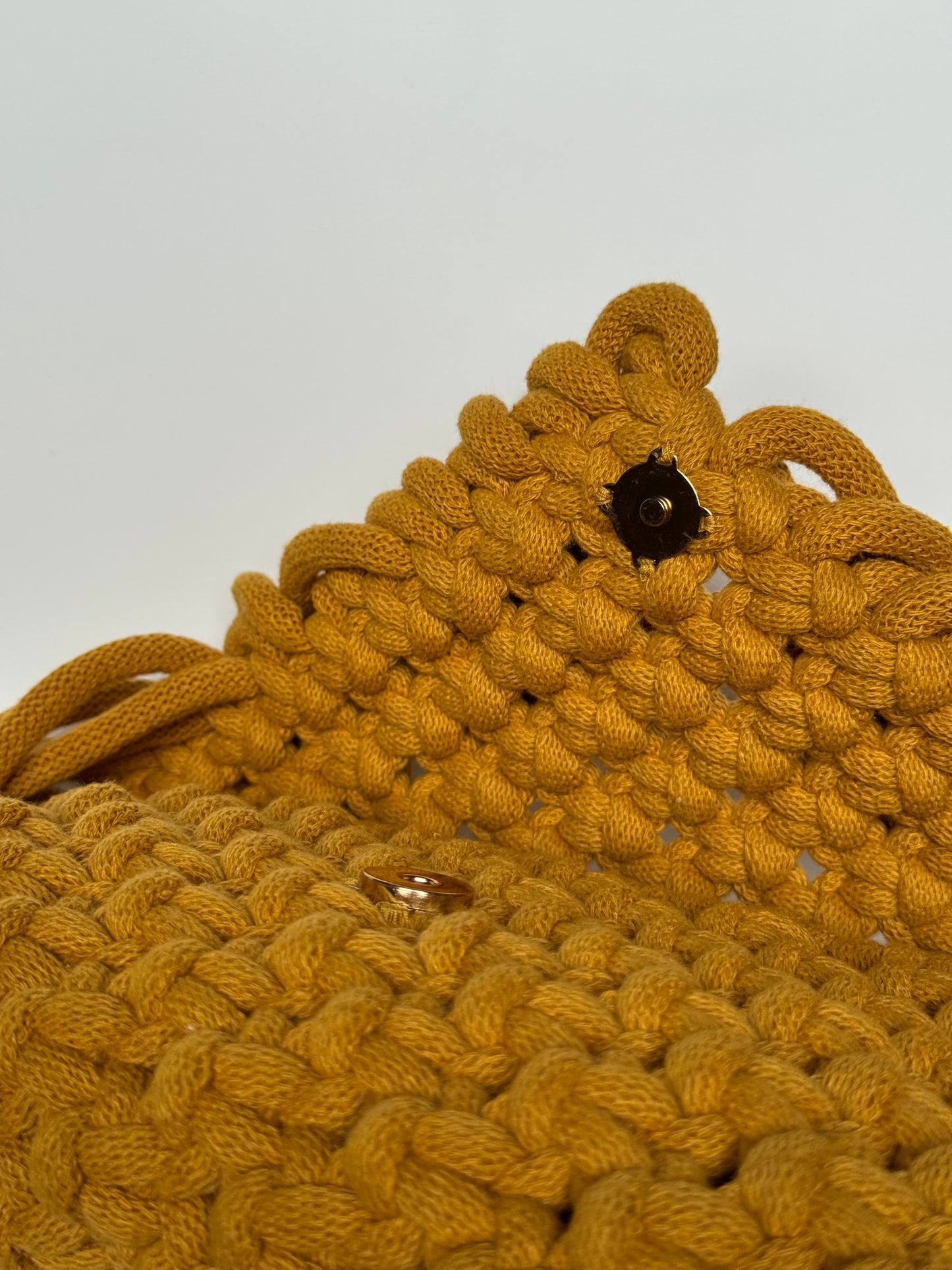 Close-up of a mustard yellow knitted bear with a white background